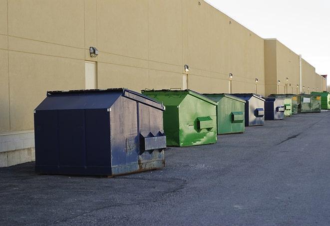 construction workers throw waste into a dumpster behind a building in Downey ID